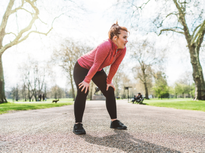 Teen girl bent over to catch her breath while running through park