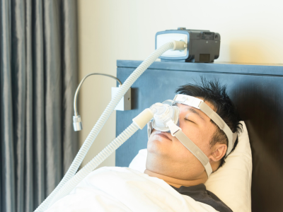 Man in bed using a CPAP machine while sleeping
