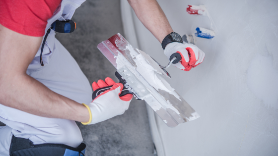 Closeup of man kneeling down with trowel with drywall mud